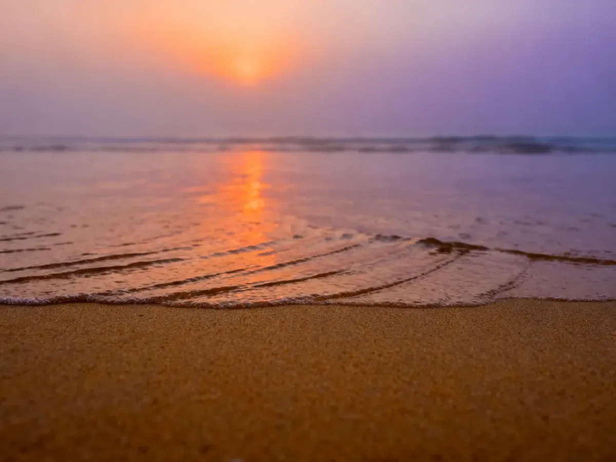 Złocista plaża w Jantarze o wschodzie słońca z malowniczymi refleksami światła na spokojnej tafli Bałtyku.