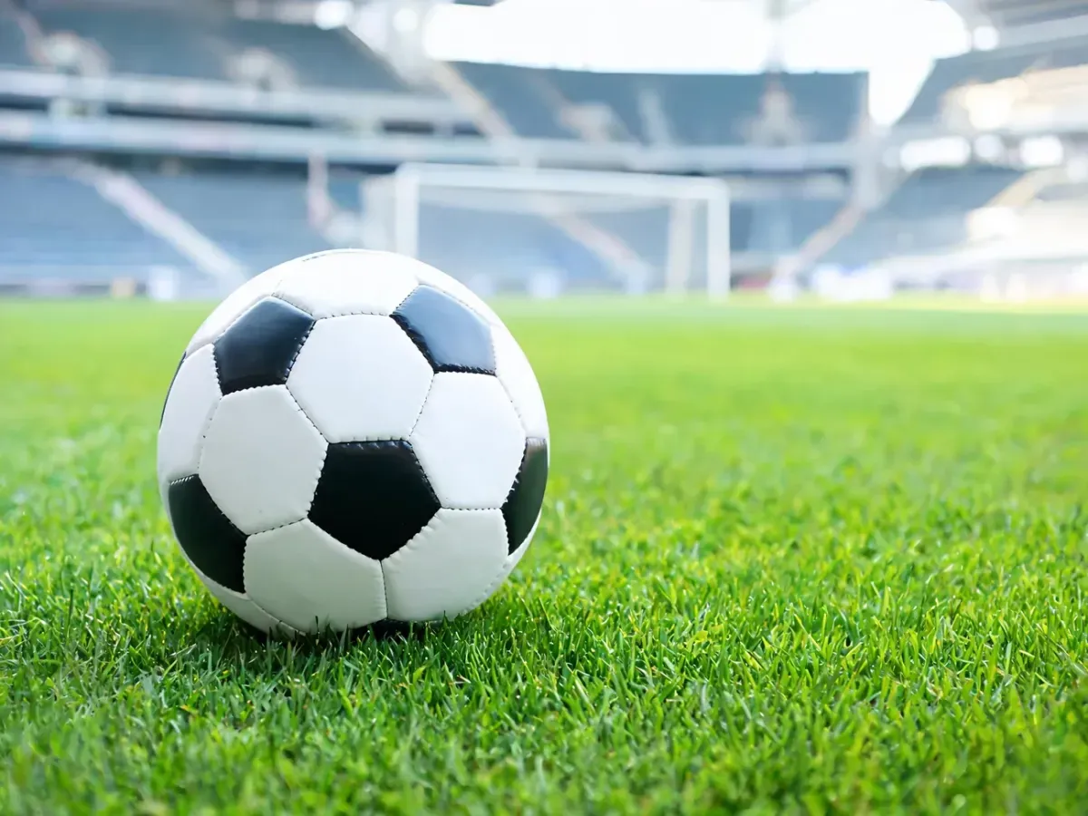 Piłka nożna na zielonej murawie stadionu, symbolizująca karierę piłkarską i trenerską Tomasza Bekasa.