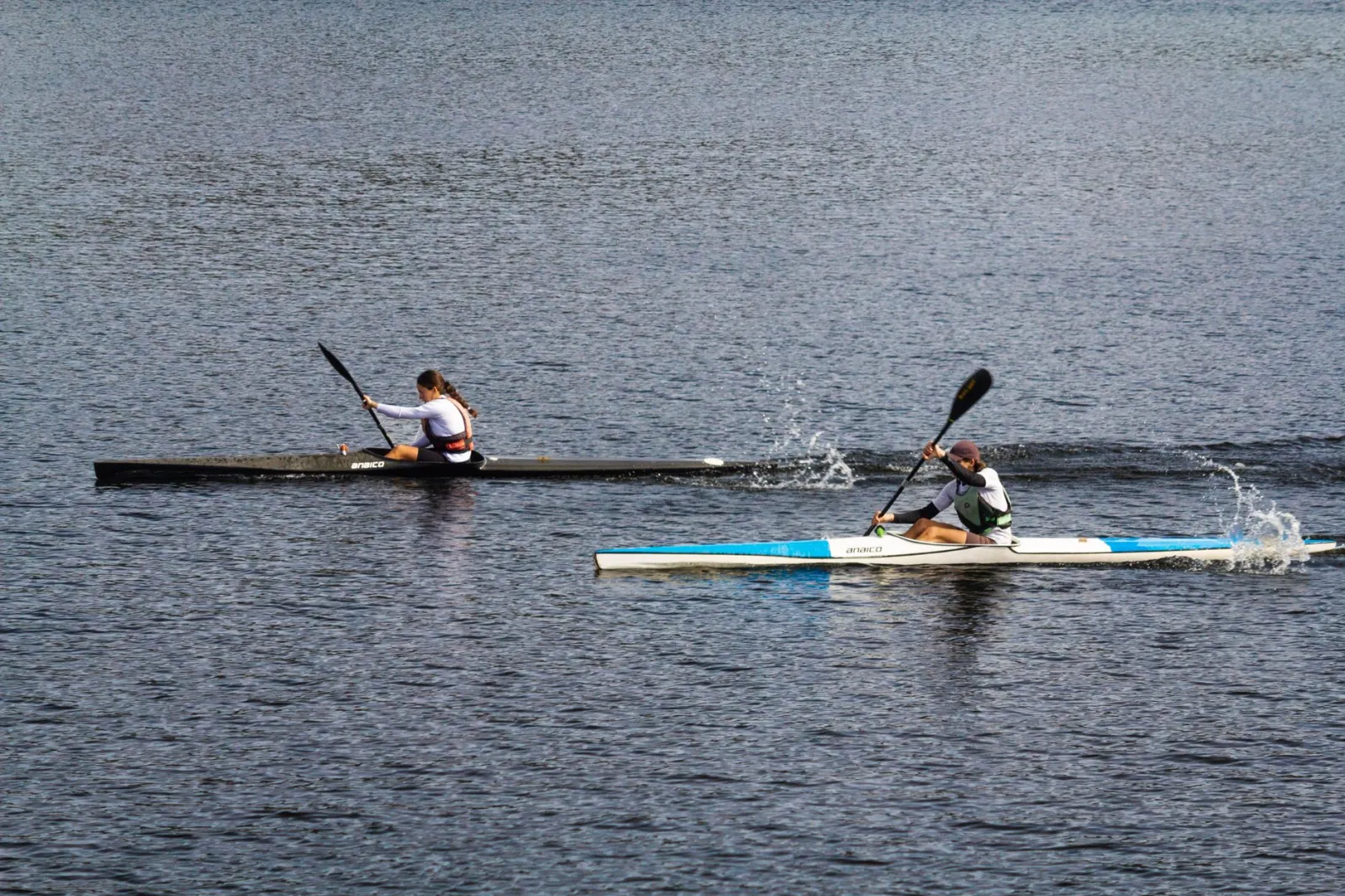 Two athletes paddle fiercely in a kayak race on a calm lake, showing competitive spirit and agility.